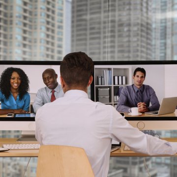 nextiva enterprises voip service man in white shirt video conferencing people on computer monitors